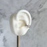 Silver ear cuff on a white ear model against a marble background