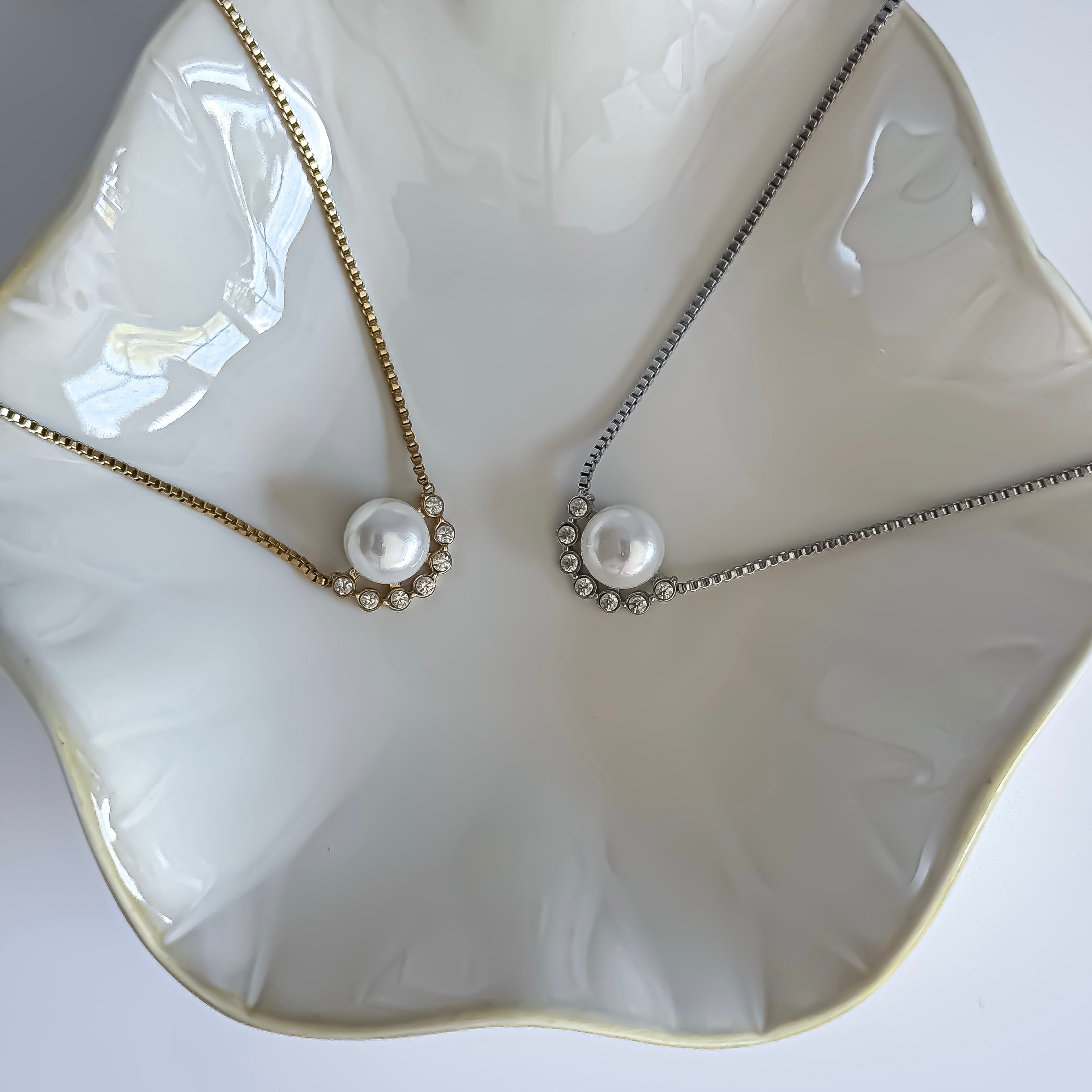 Two pearl necklaces on a decorative white dish.