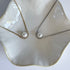 Two pearl necklaces on a decorative white dish.