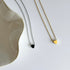 Two necklaces one gold and one silver with heart pendants on a white surface