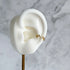 Gold ear cuff on a white ear model with a marble background