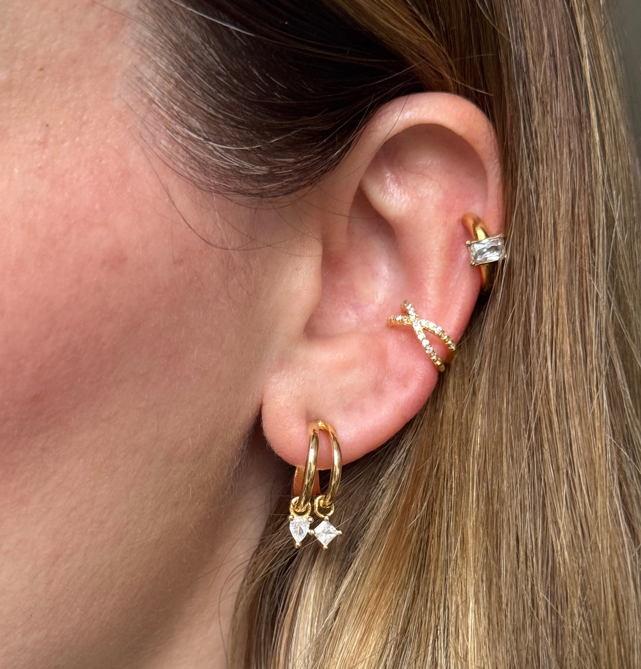 Close-up of an ear with gold earrings and ear cuff.