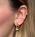 Close-up of an ear with gold earrings and ear cuff.