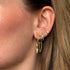 Close-up of an ear with gold hoop earrings and a small diamond earring.