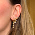 Close-up of an ear wearing gold hoop earrings with star and diamond designs.