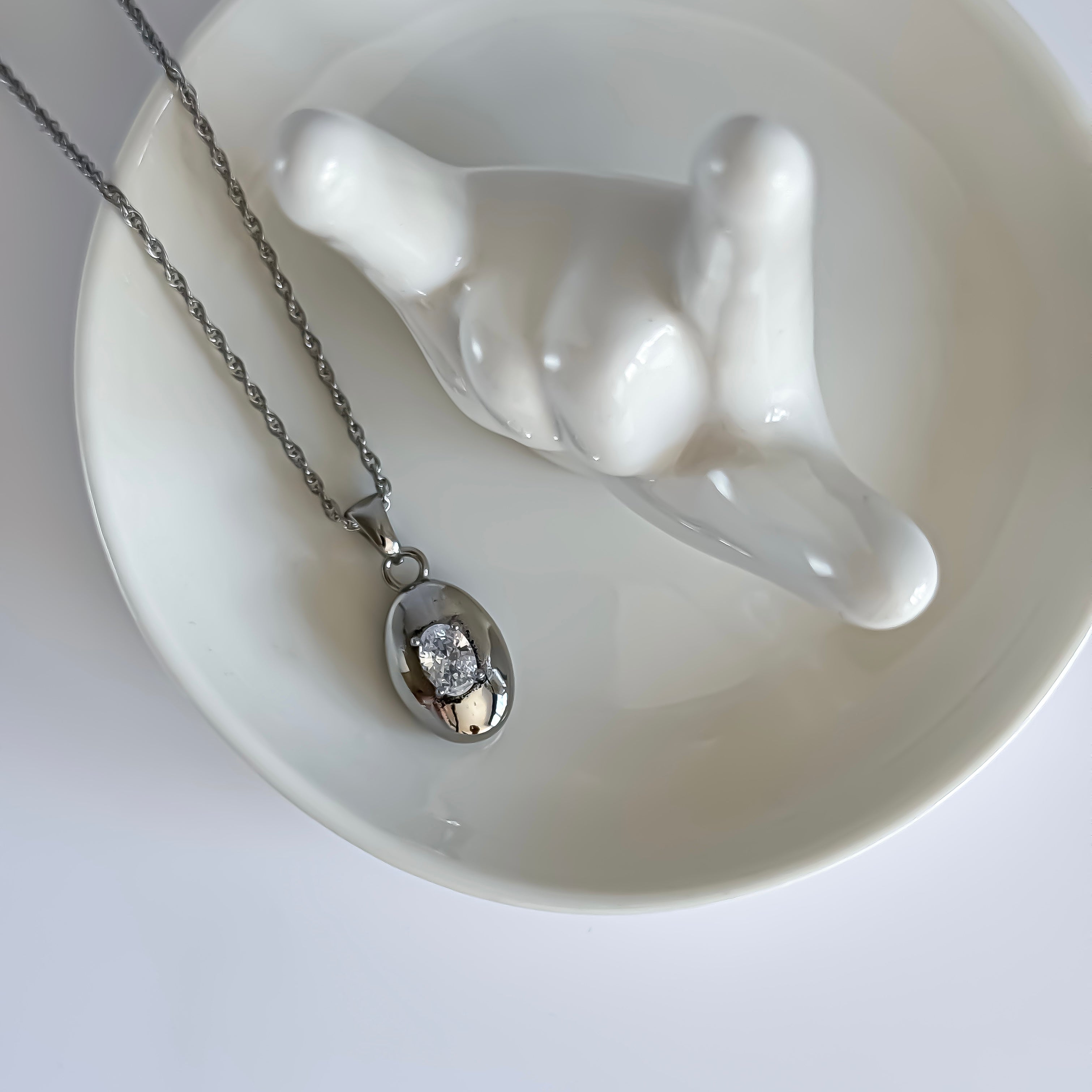 Silver necklace with a pendant on a white stand