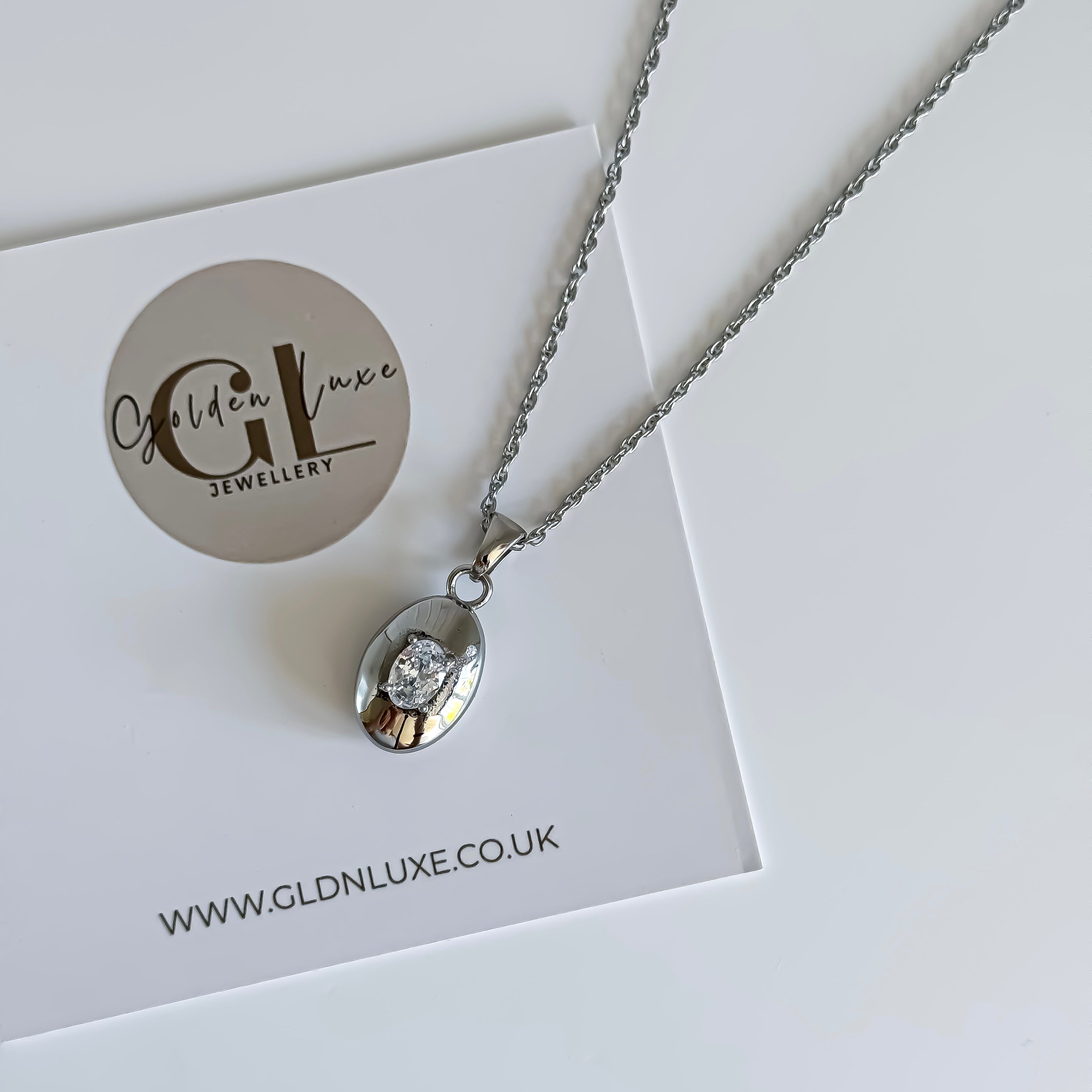 Silver necklace with a pendant on a card featuring Golden Luxe Jewellery branding.
