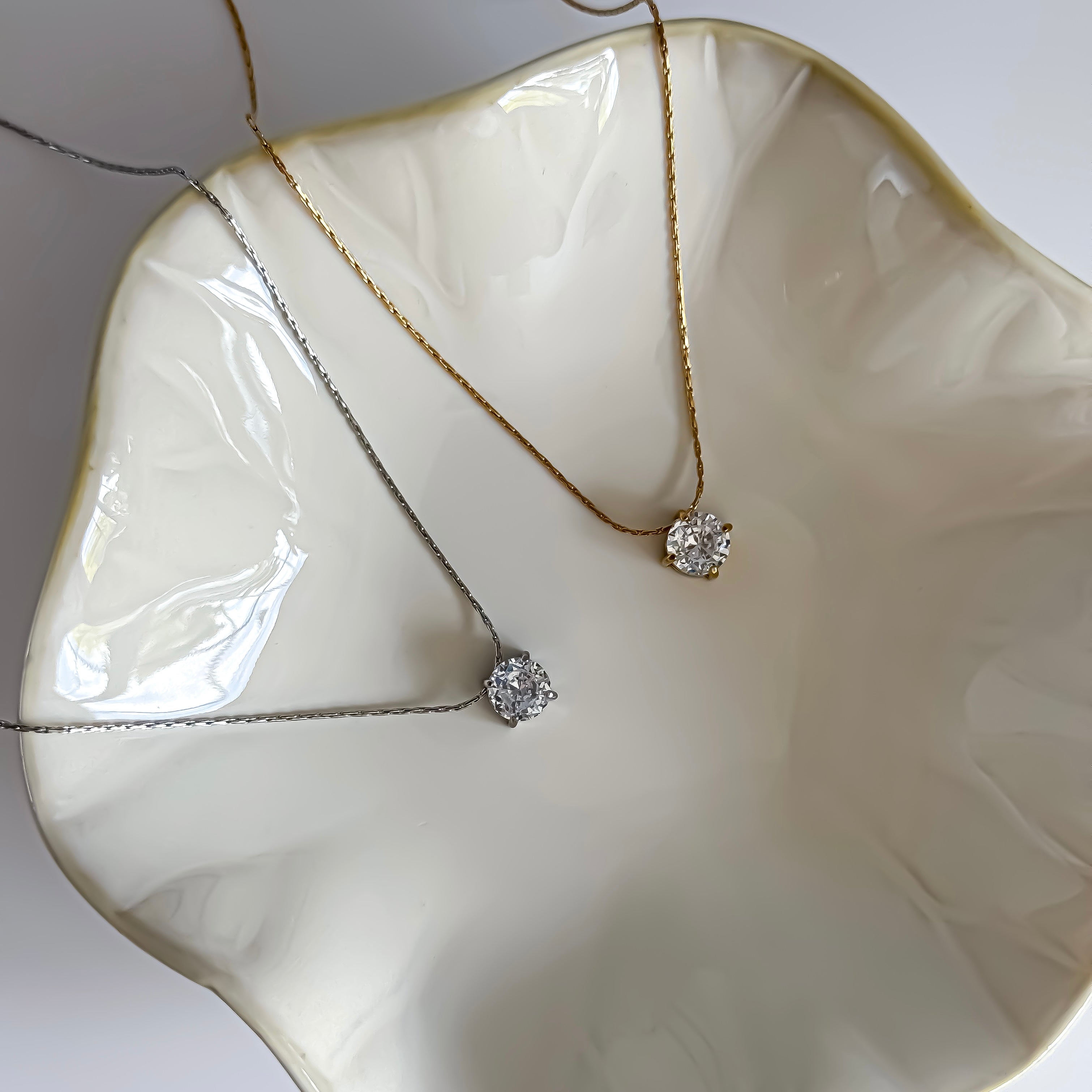 Two diamond necklaces on a white ceramic dish
