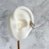Close-up of an ear with a gold and silver ear cuff on a marble background