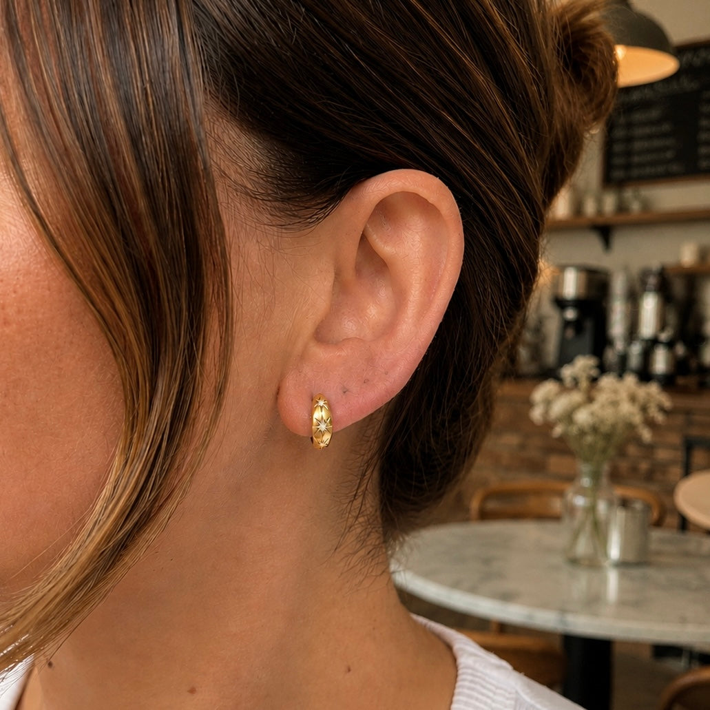 Woman wearing gold-plated Celeste Starburst huggie earrings with cubic zirconia