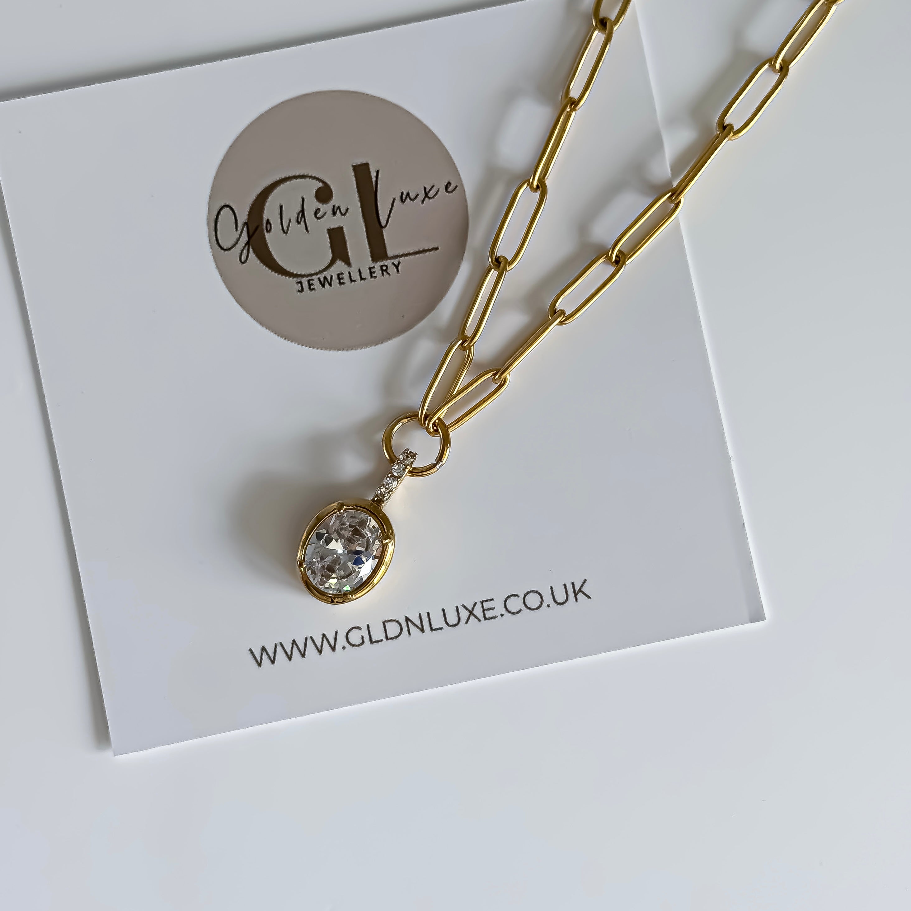 Gold necklace with a pendant on a card featuring 'Golden Luxe Jewellery' and their website.