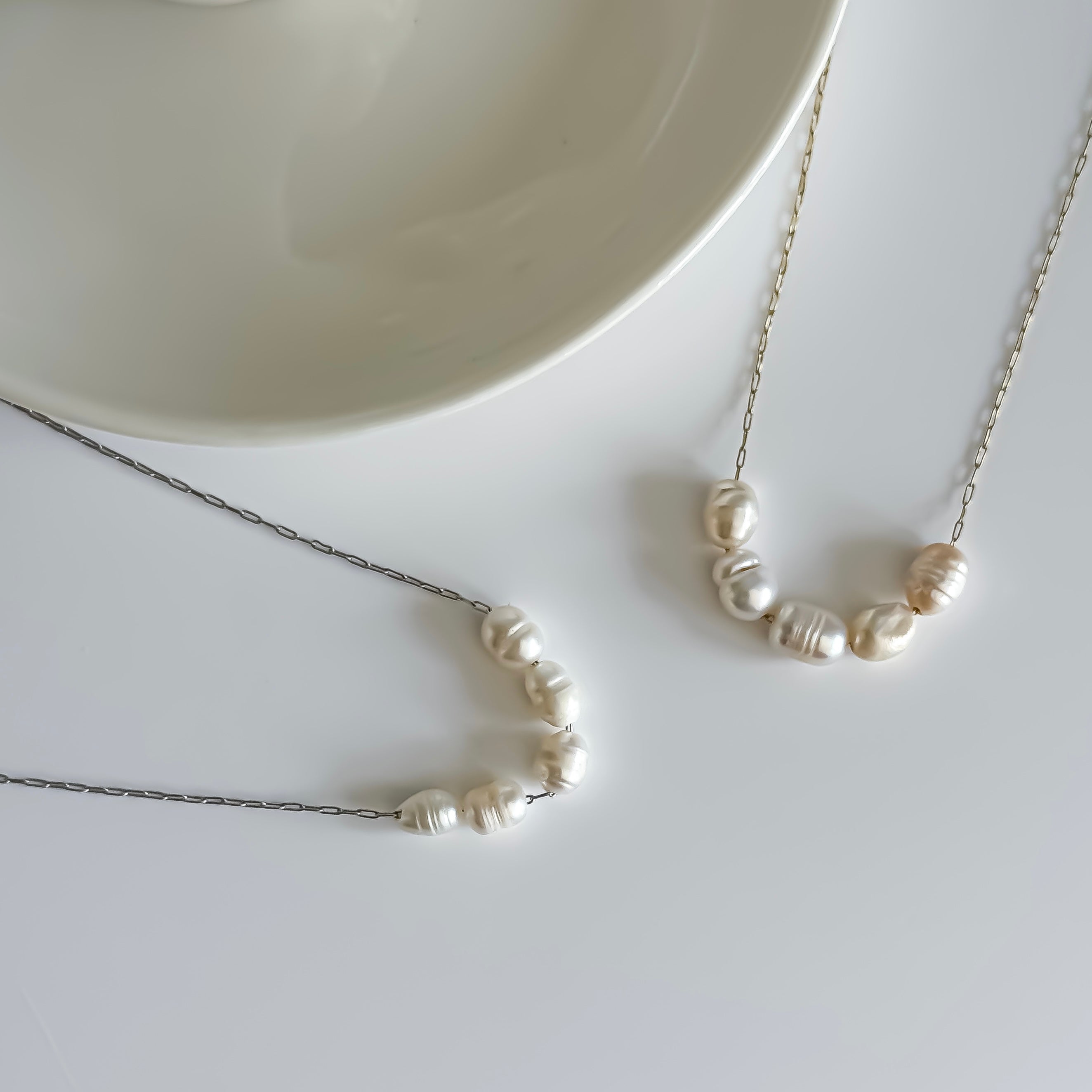 Pearl necklace on a white surface with a neutral background