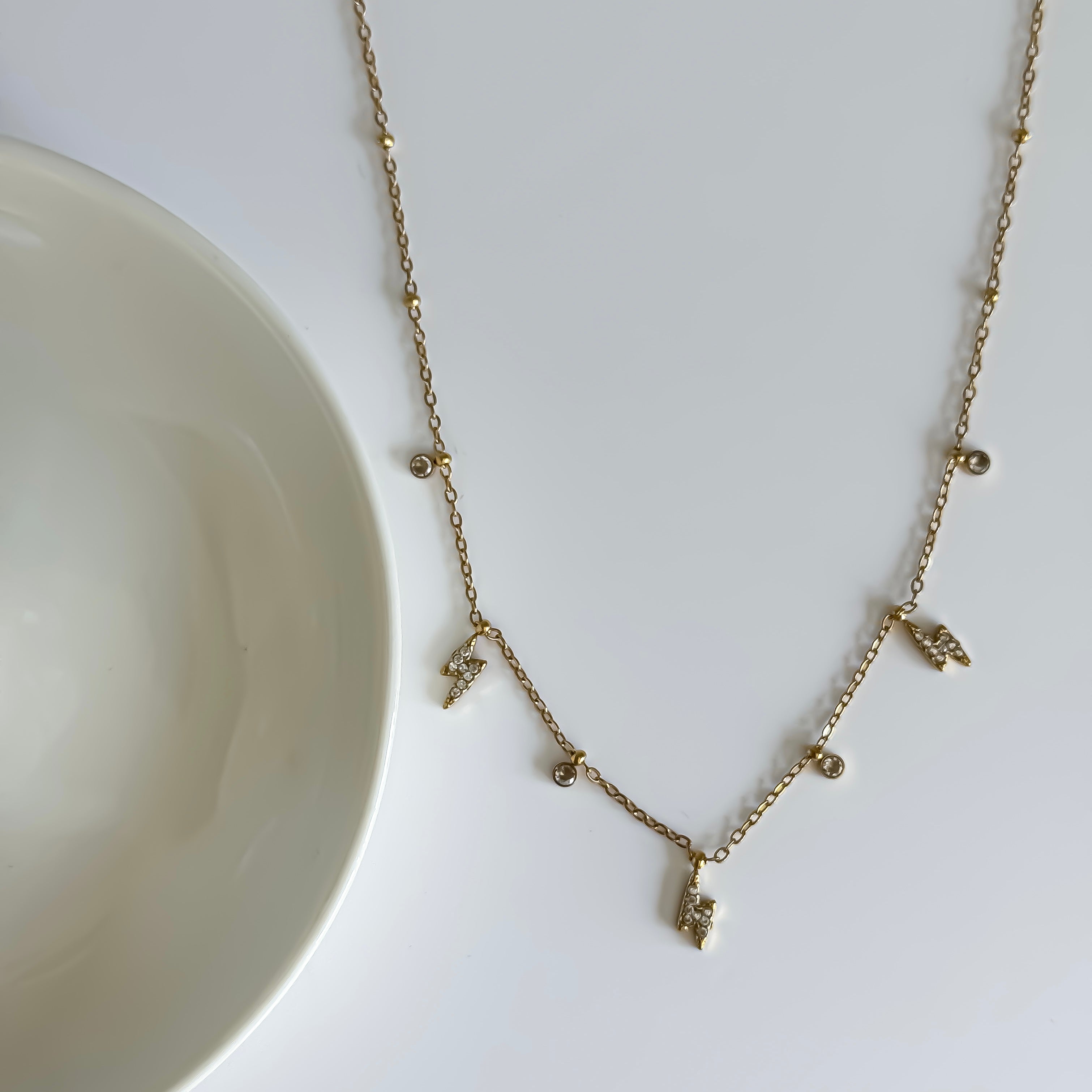 Gold necklace with small pendants on a white surface
