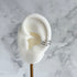 White ear model with a silver ear cuff on a marble background