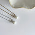 Two pearl necklaces one in gold and one in silver on a white surface