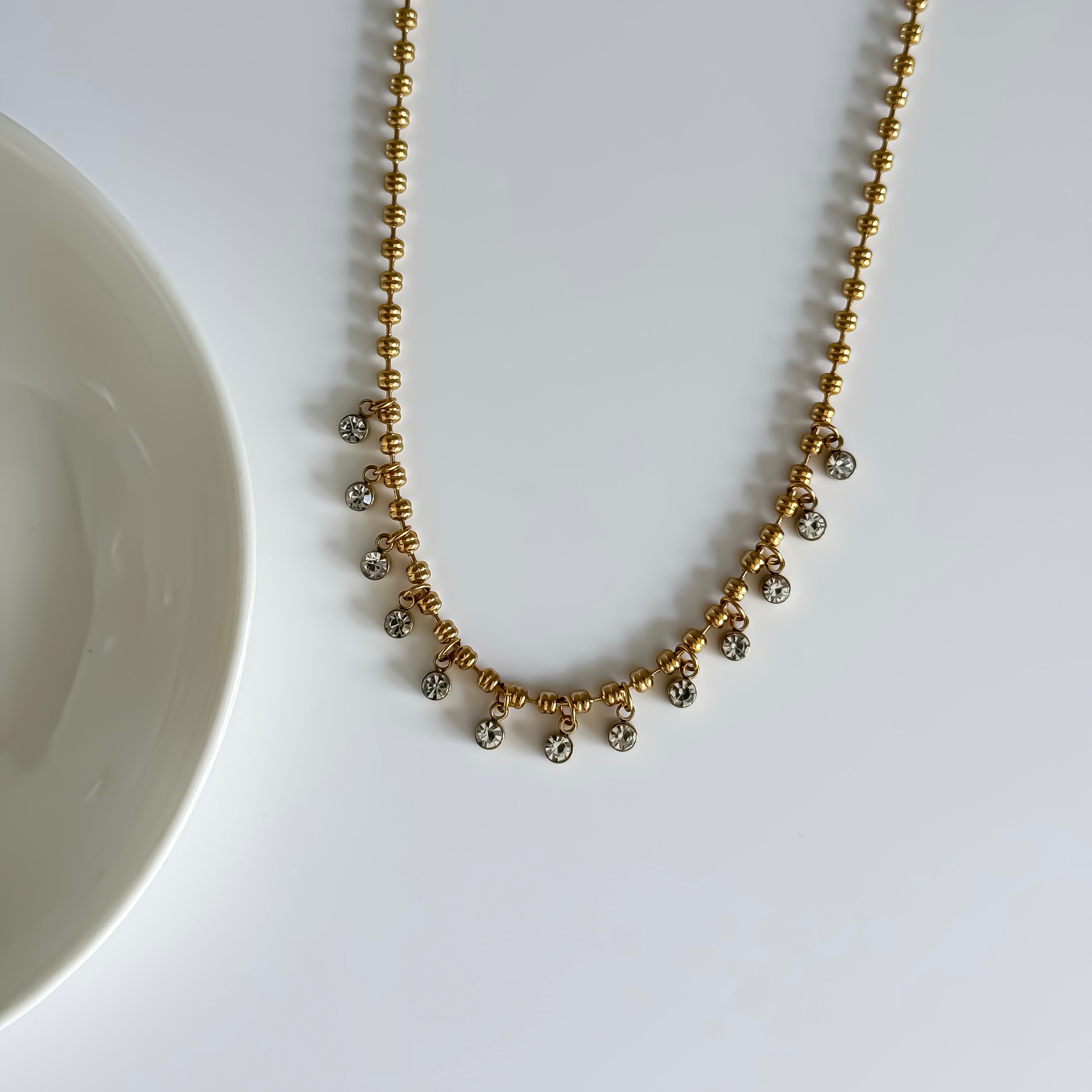 Gold necklace with small beads on a white background