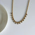 Gold necklace with small beads on a white background