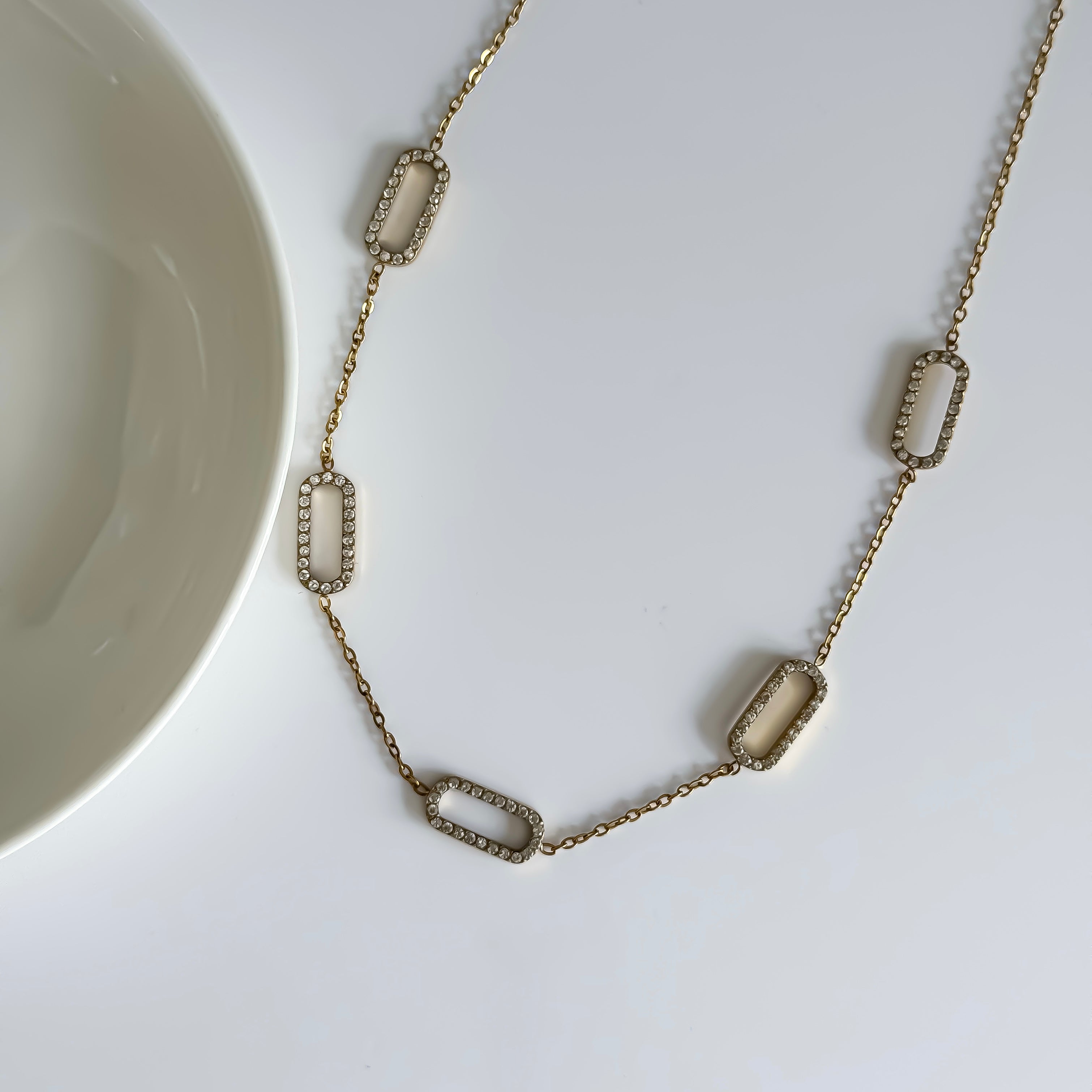 Gold necklace with rectangular links on a white surface