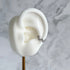 Silver ear cuff on a white ear model with a marble background