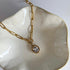 Gold chain necklace with a pendant on a white dish