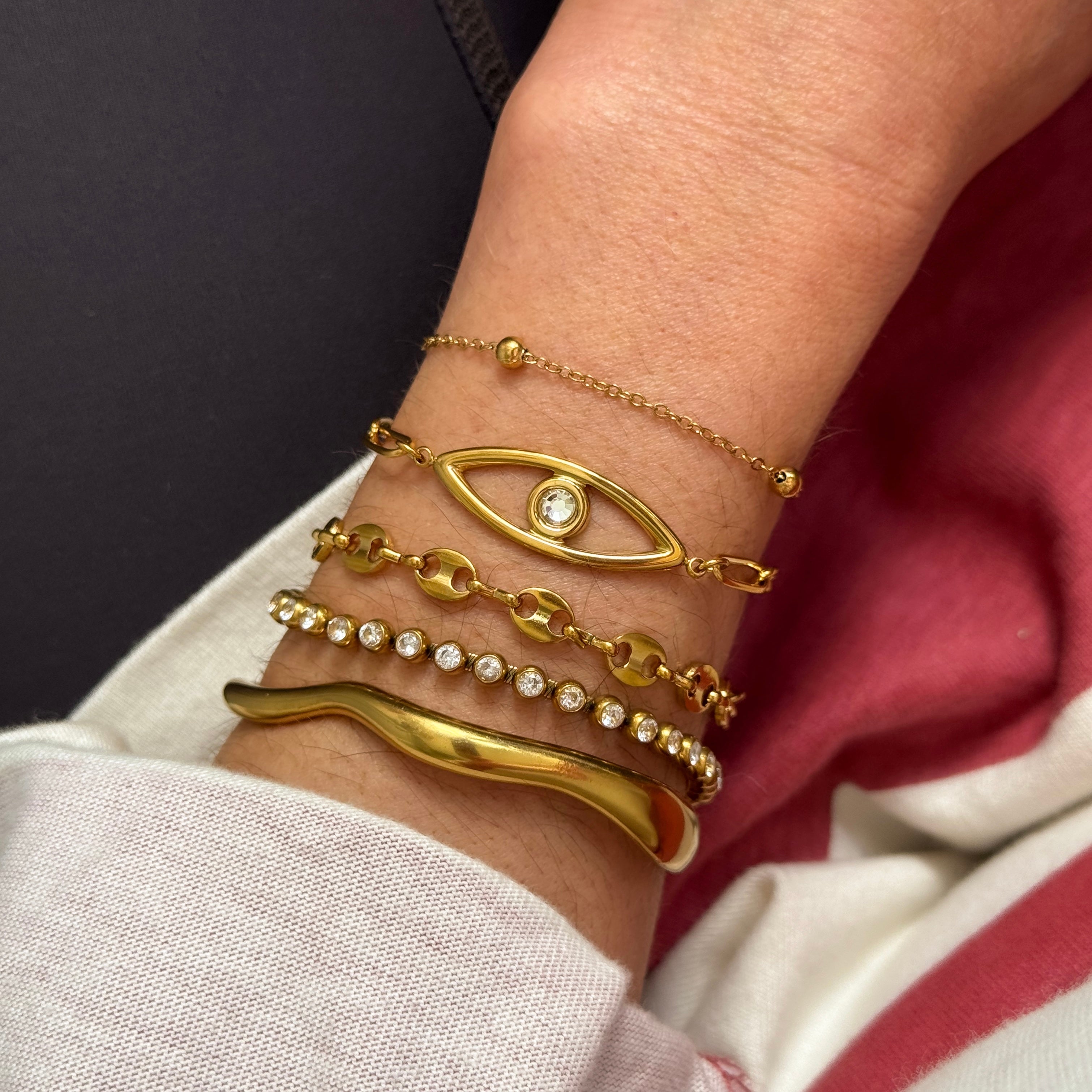 Gold bracelets on a wrist with a dark background
