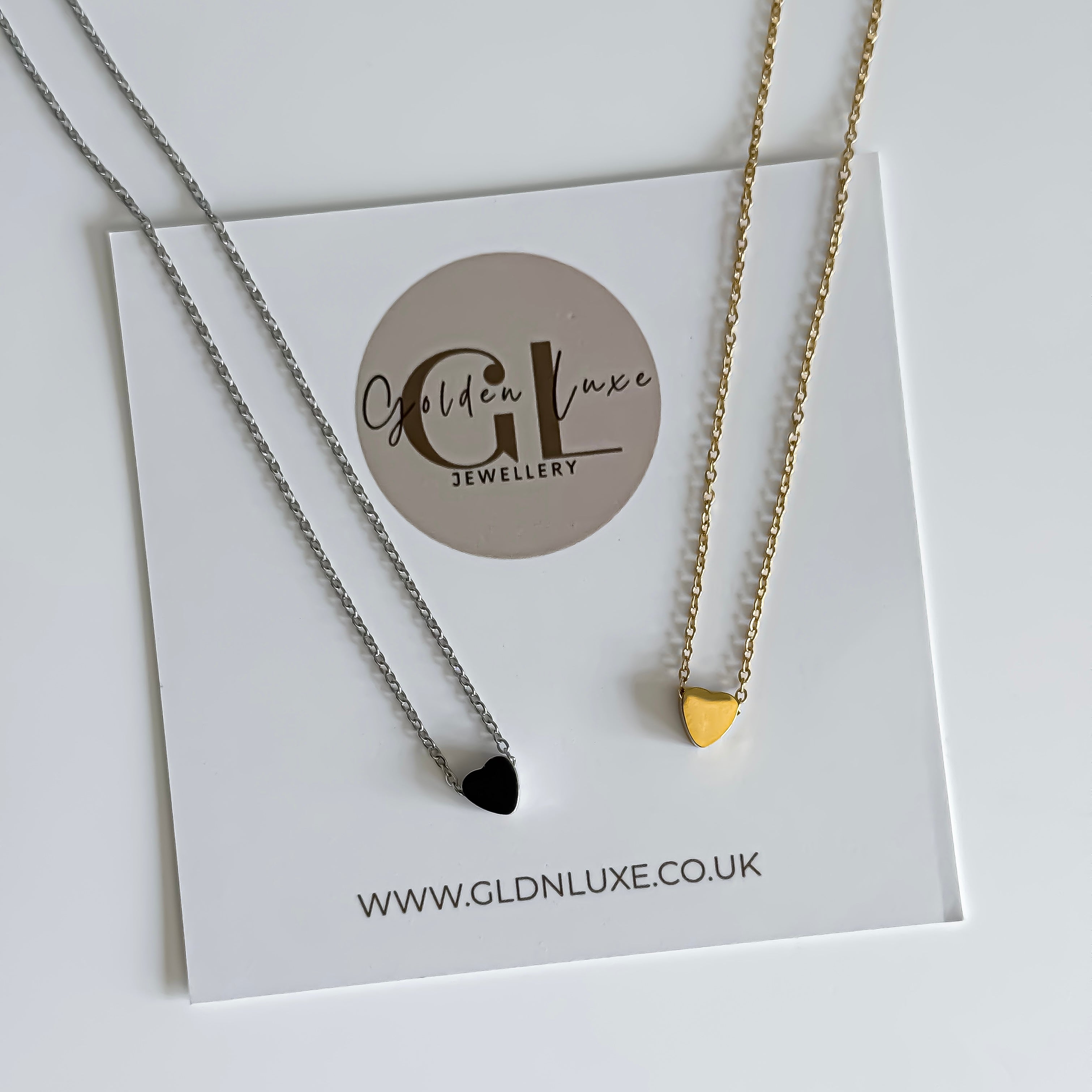Two necklaces on a Golden Luxe Jewellery card with a gold and silver heart pendant.