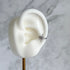 Silver star-shaped ear cuff on a white ear model with a marble background