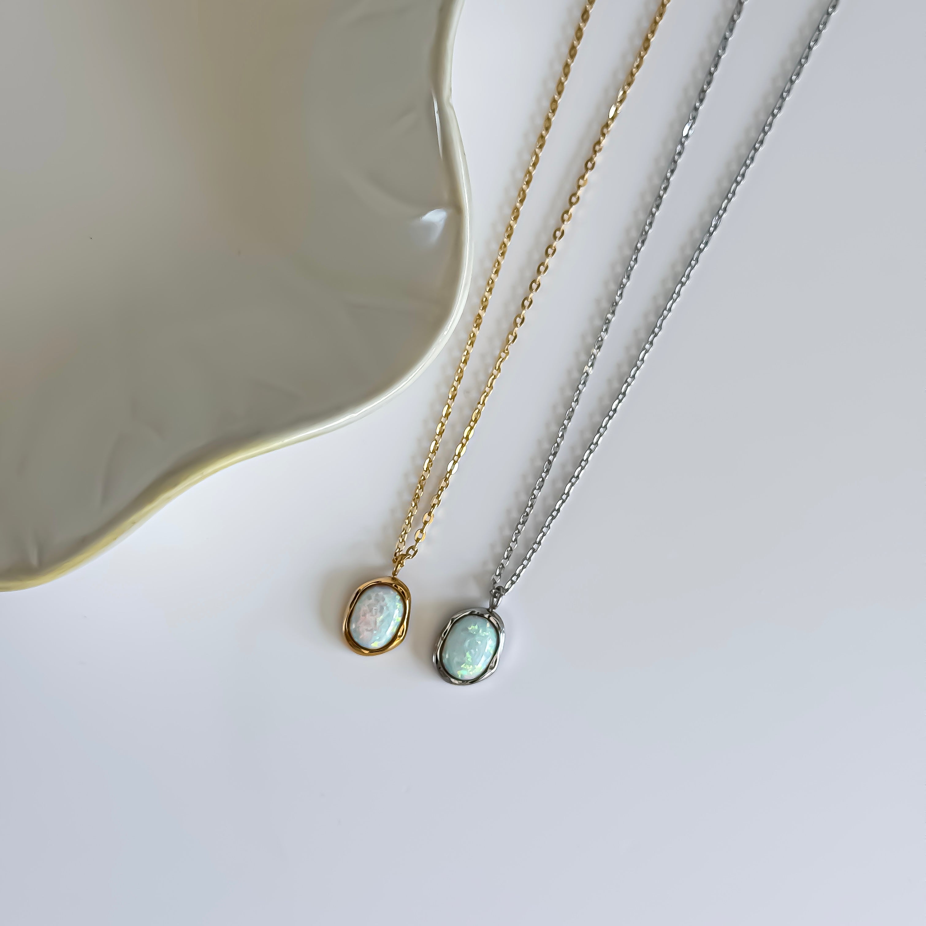 Two opal pendant necklaces on a light background