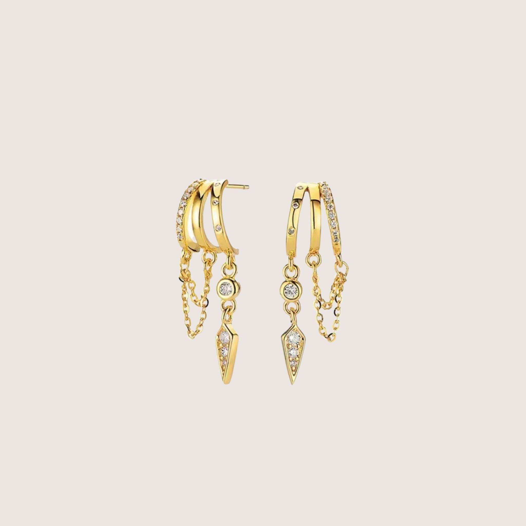 Gold hoop earrings with chain and gemstone details on a beige background