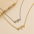 Two personalized name necklaces with cursive script pendants reading 'Nysef', one in gold and one in silver, displayed on a beige background with a stone prop.